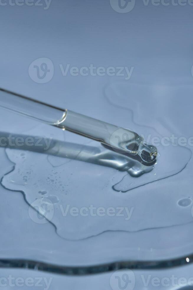 Dropper with serum or cosmetic oil on a blue background. photo