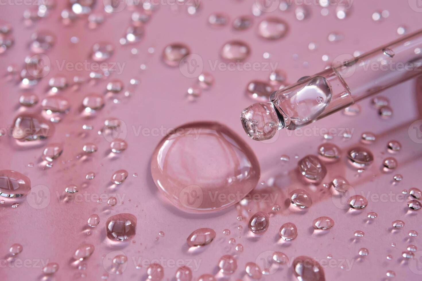 Pipette, drop and splashes of micellar water on a pink background. photo