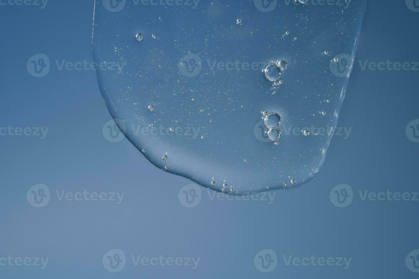 The texture of a gel or shampoo flowing down on a blue background. photo