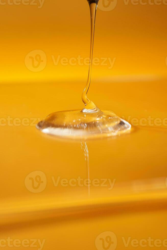 A drop of body gel or shampoo pouring from above on a yellow saturated background. photo