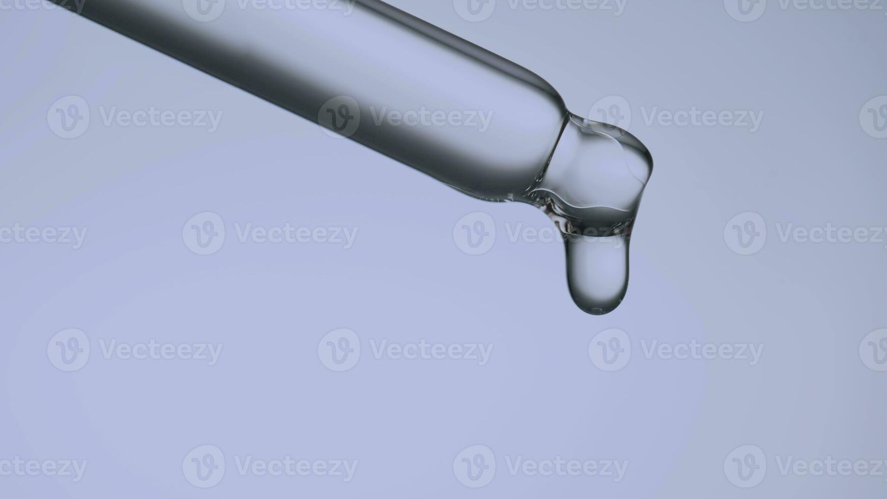 Pipette with a drop of cosmetic product on a purple background. photo