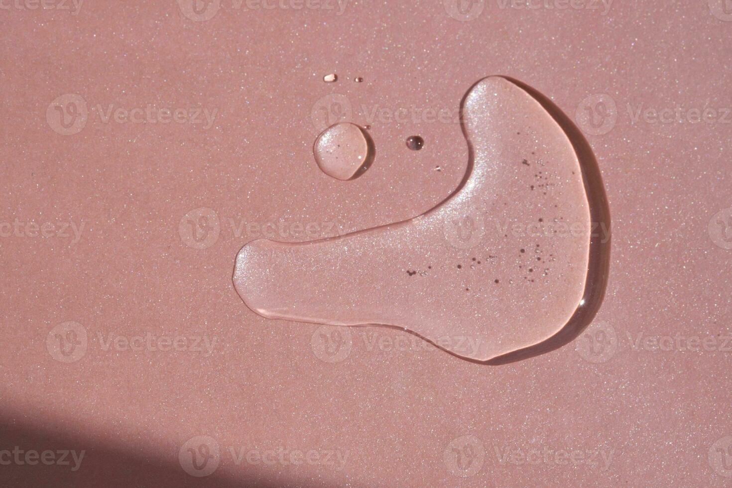 A drop of cosmetics or perfume on a pink background. photo