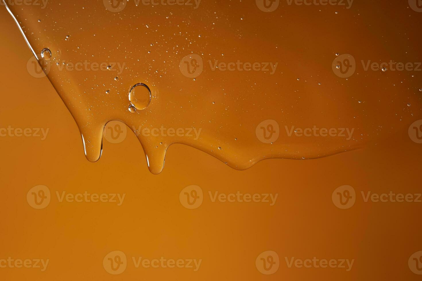 A drop of body gel or shampoo flowing down on a yellow saturated background. Texture. photo