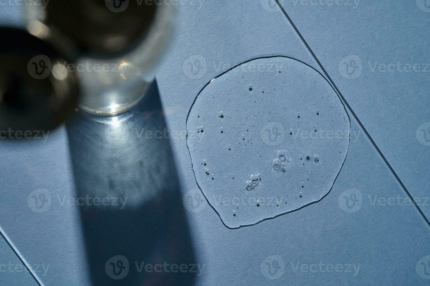 A bottle of shampoo or gel and a drop of the remedy on a blue background. photo