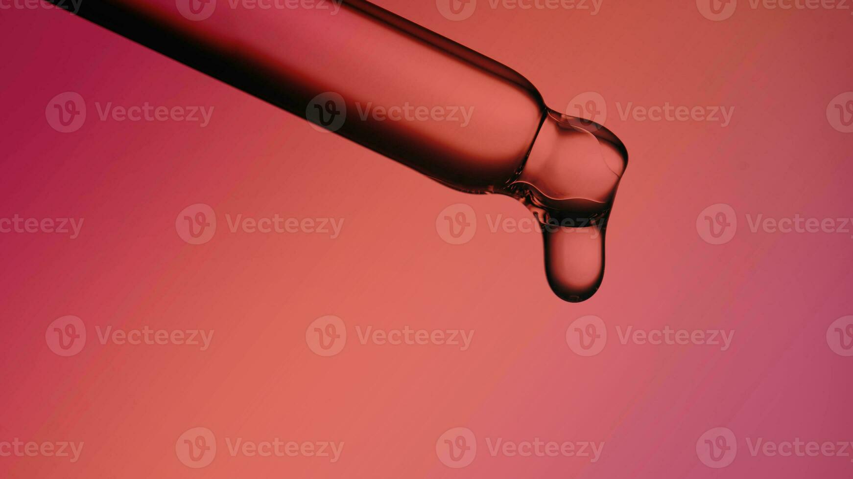 Pipette with a drop of cosmetic product on a red background. photo