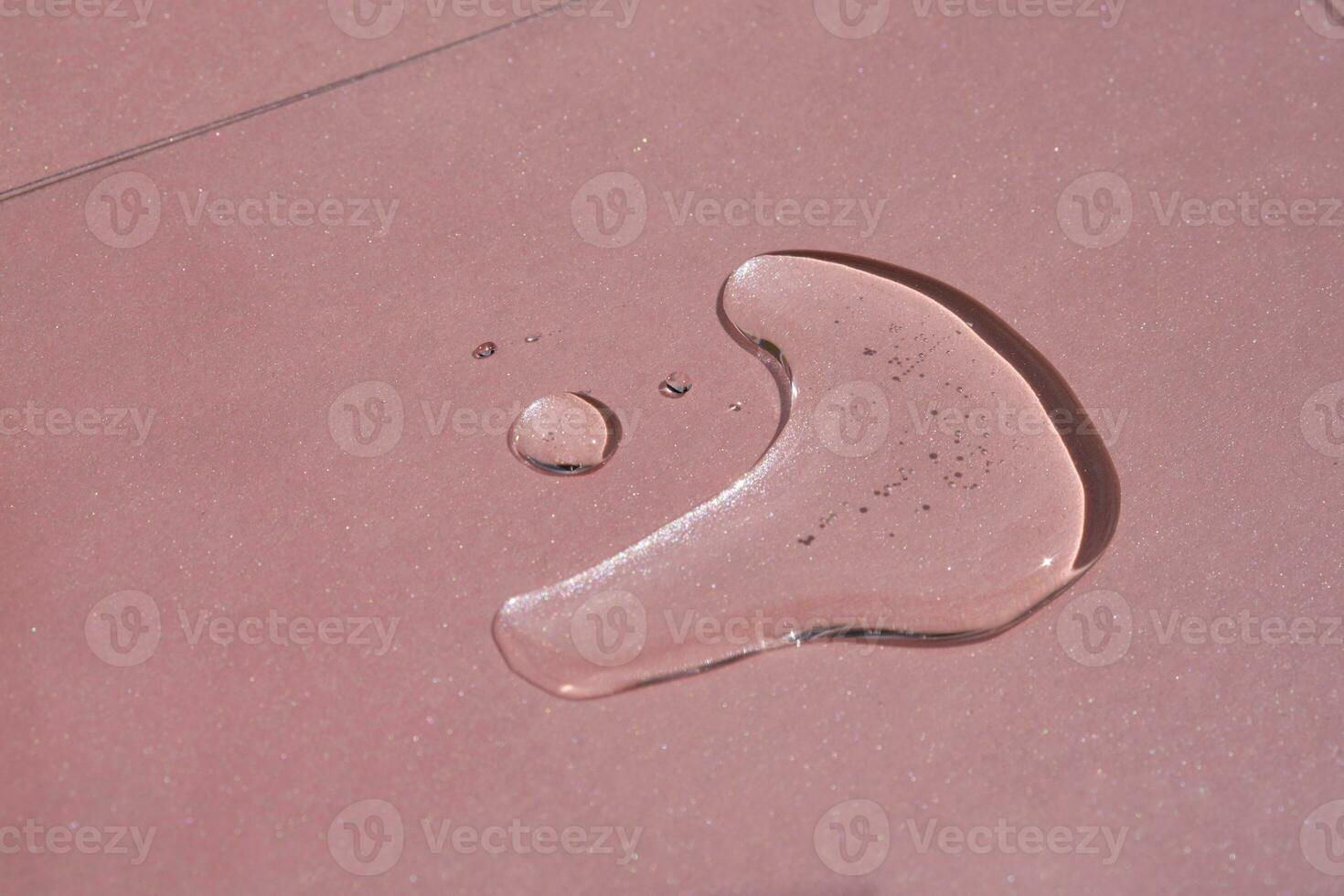 A drop of cosmetics or perfume on a pink background. photo