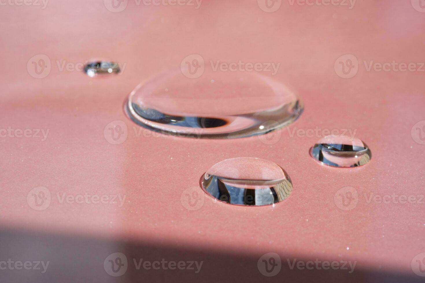 Three drops of cosmetics or perfume on a pink background. photo