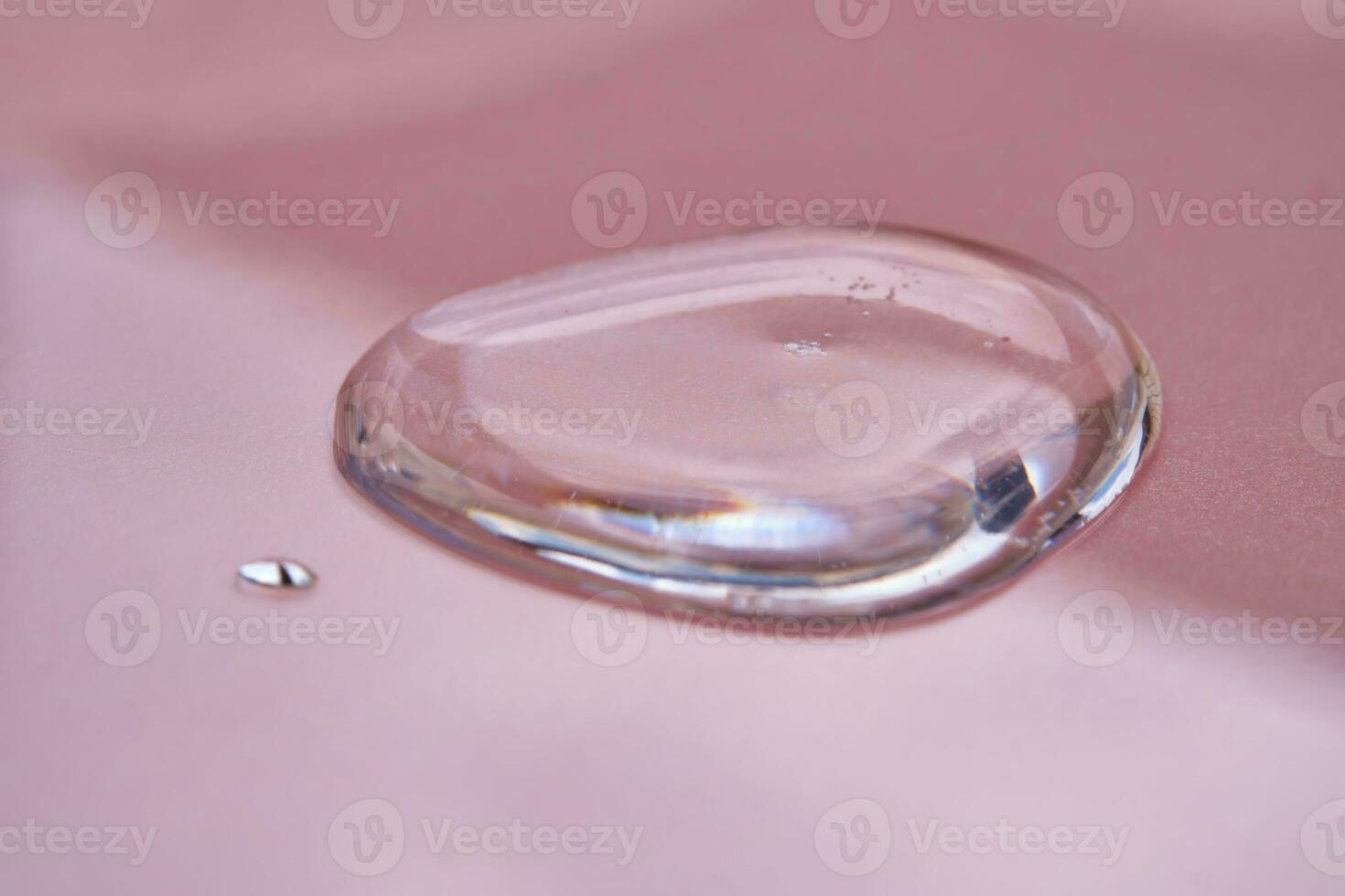 A drop of cosmetics or perfume on a pink background. photo