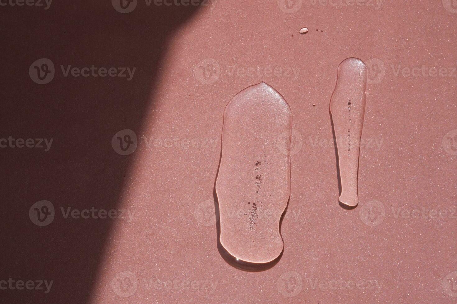 Two elongated drops of cosmetics or perfume of a plant on a pink background. photo