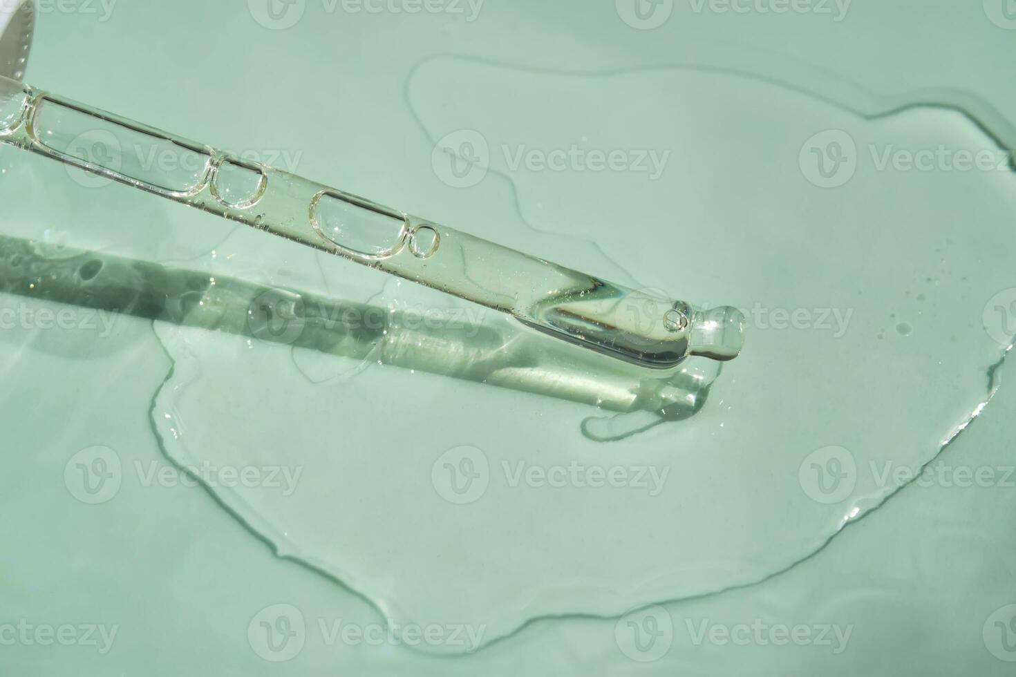 Dropper with serum or cosmetic oil on a green background. photo