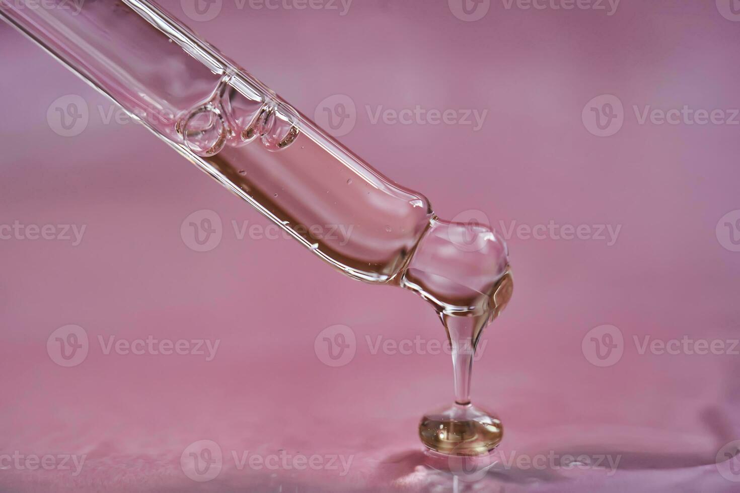 Dropper with serum or cosmetic oil on a pink background. photo