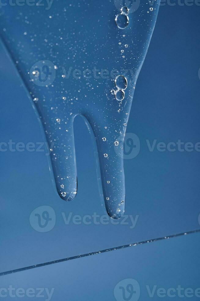 The texture of a gel or shampoo flowing down on a blue background. photo