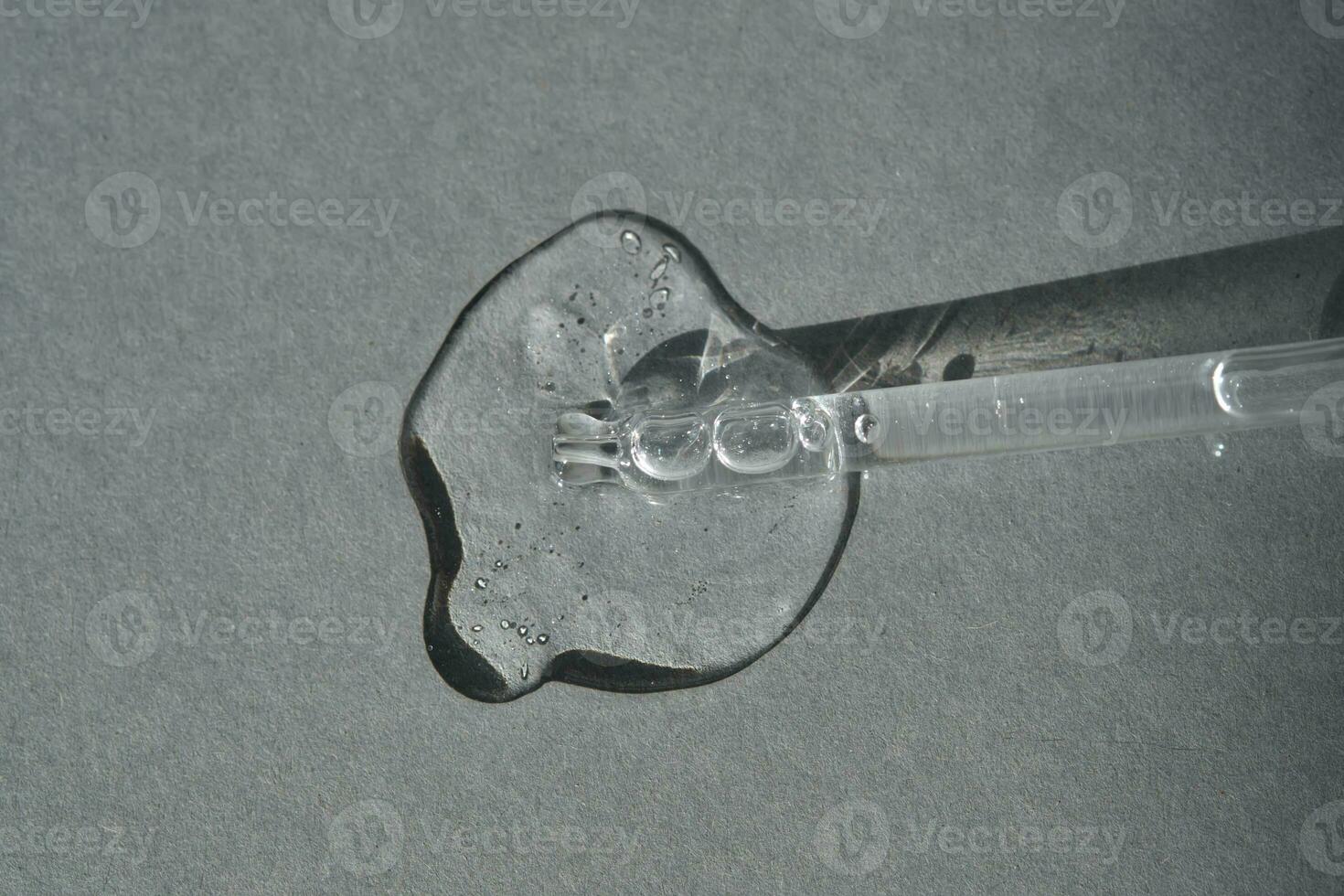 Pipette with spilled cosmetic oil or serum on a gray background. photo