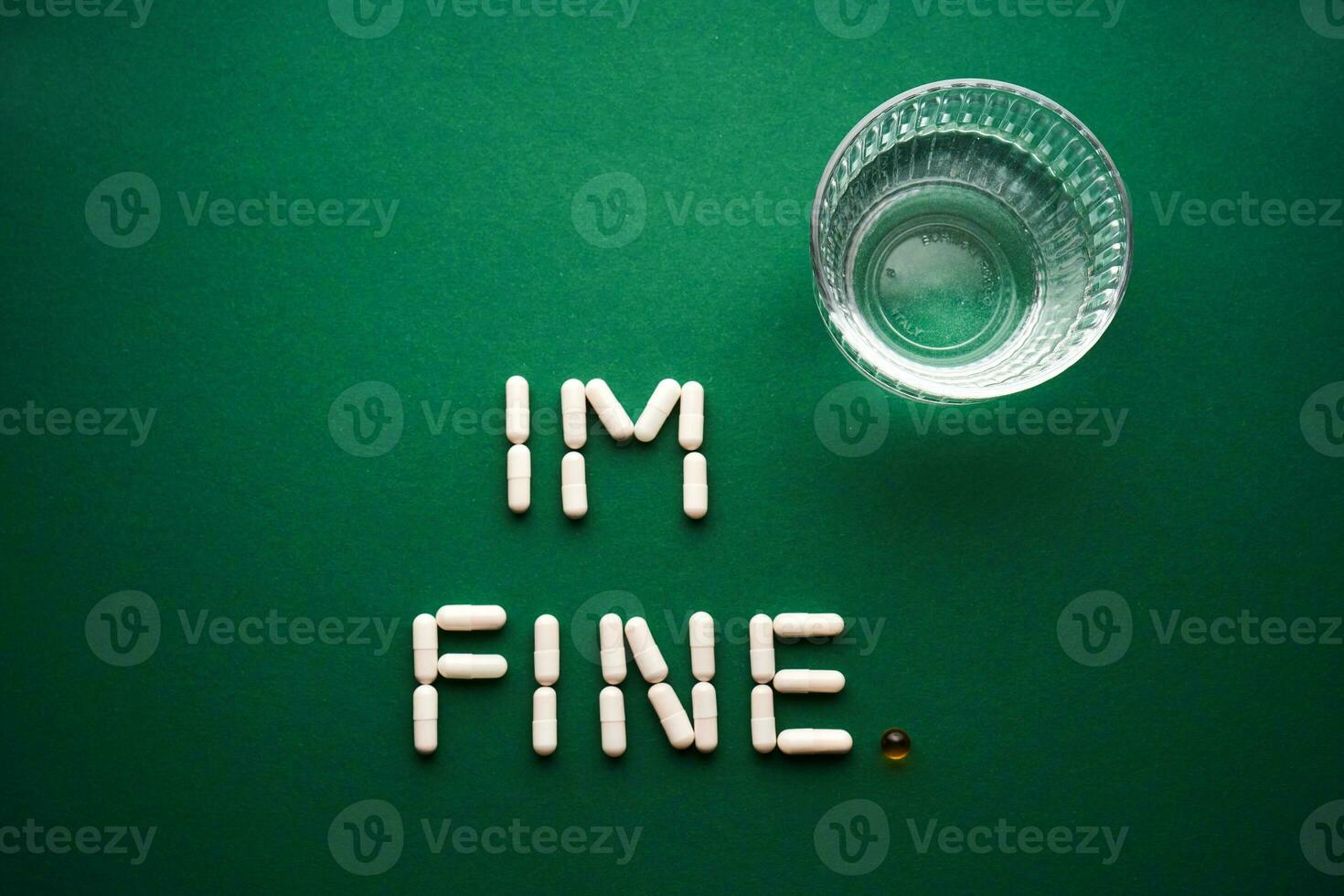 Capsules formed into the inscription I'm fine on a green background with a glass of water. photo