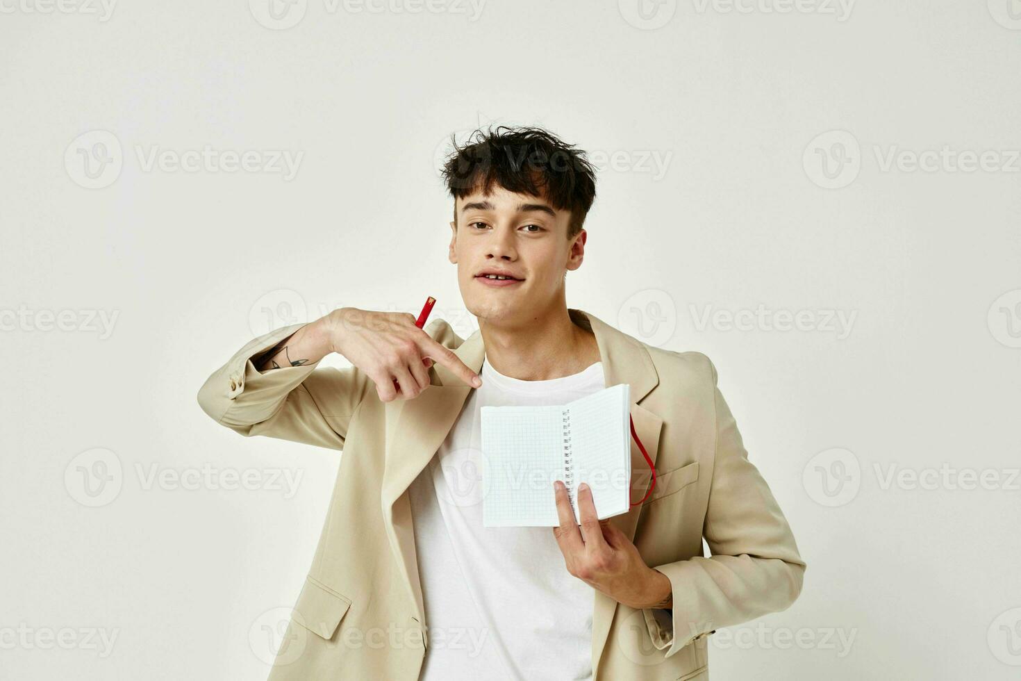 handsome guy posing with a notepad in a suit light background unaltered photo