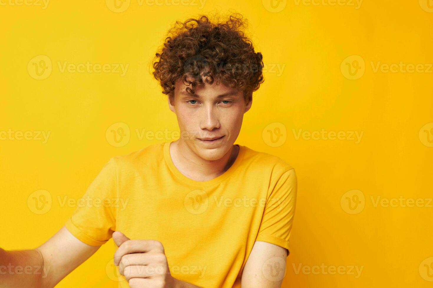retrato de un joven Rizado hombre vistiendo elegante amarillo camiseta posando amarillo antecedentes inalterado foto