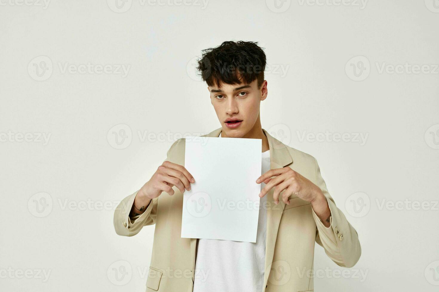 A young man in a beige suit copy-space folder with papers light background unaltered photo