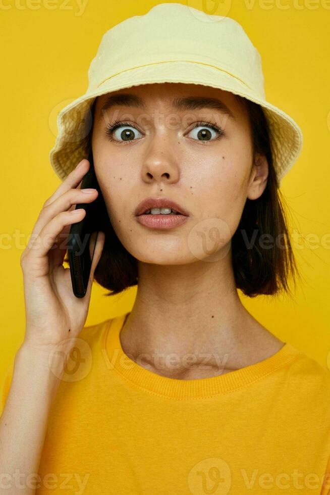 atractivo mujer en un amarillo sombrero juventud estilo casual hablando en el teléfono aislado antecedentes foto