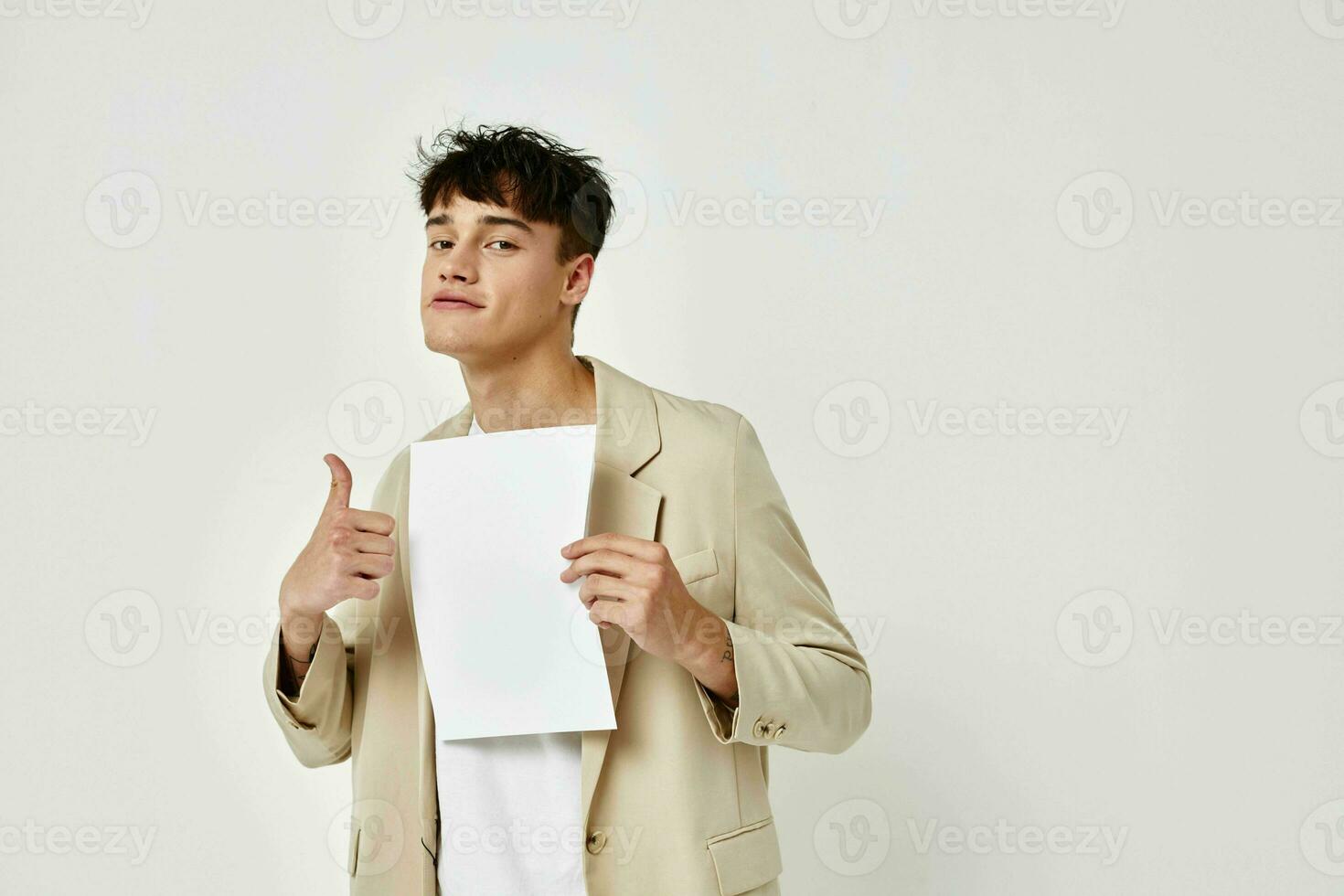A young man in a beige suit copy-space folder with papers light background unaltered photo