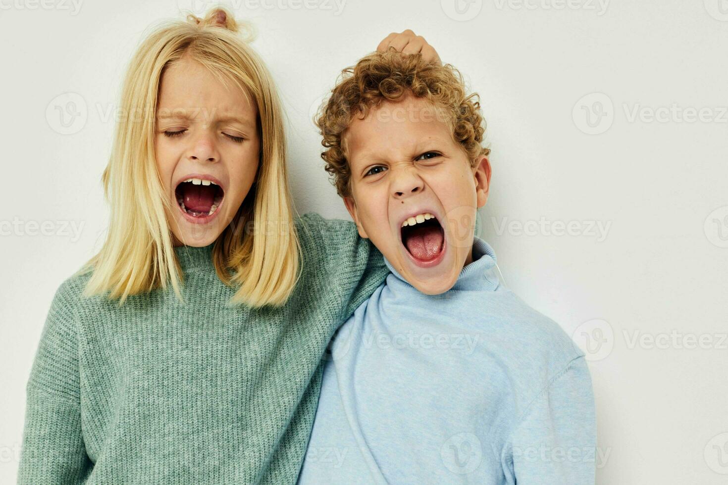 Portrait of cute children in multi-colored sweaters posing for fun light background photo