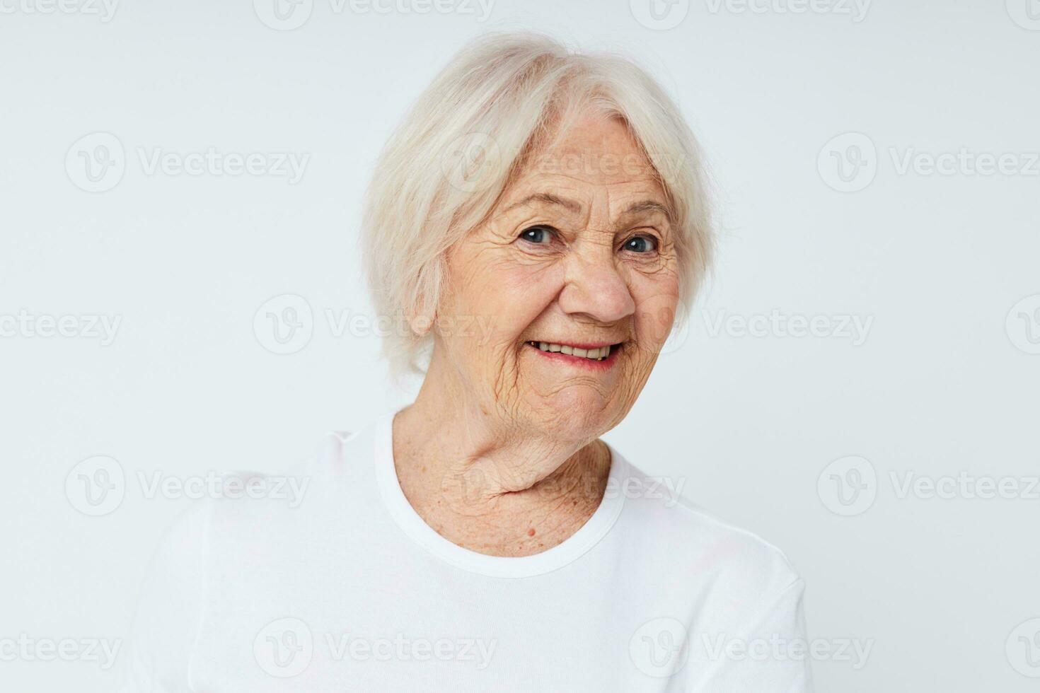 de cerca de un alegre mayor mujer en un blanco camiseta foto