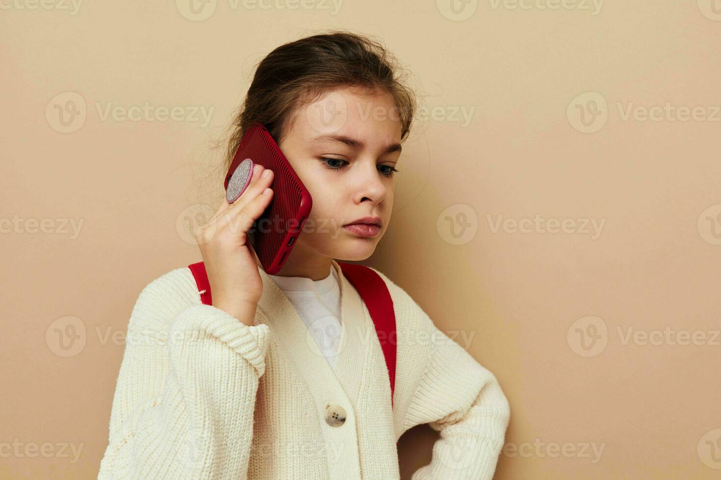 Portrait of happy smiling child girl with phone posing red backpack isolated background photo