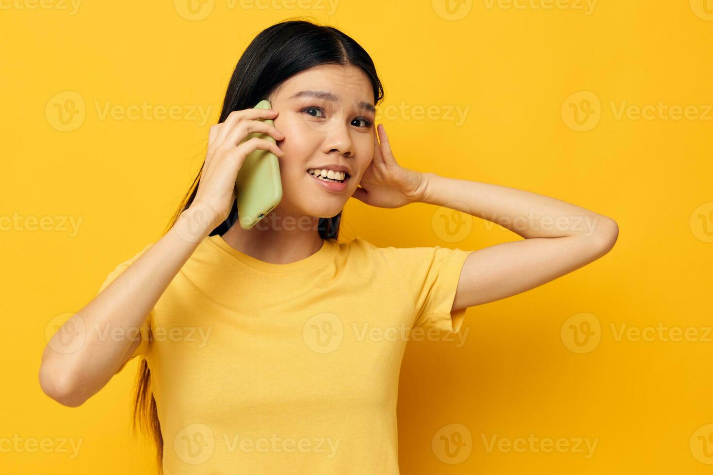 pretty brunette talking on the phone posing technology yellow background unaltered photo