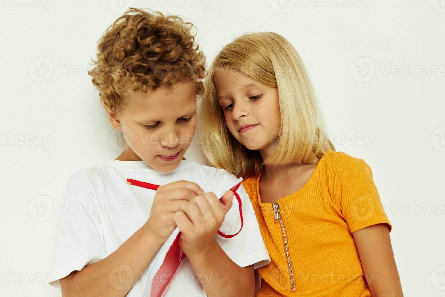 picture of positive boy and girl fun in colorful t-shirts with a notepad isolated background unaltered photo