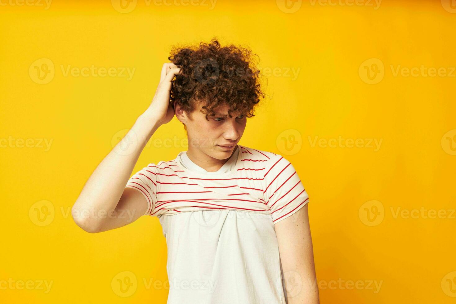 cute red-haired guy putting on a striped t-shirt posing isolated background unaltered photo