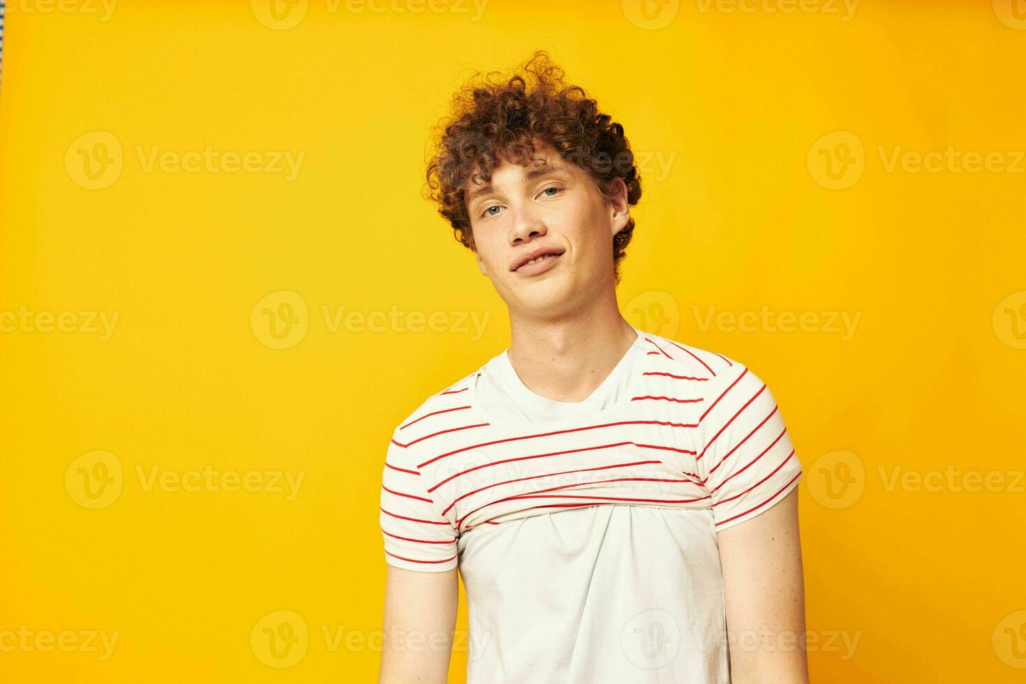 retrato de un joven Rizado hombre en un blanco camiseta sostiene un a rayas camiseta Moda juventud estilo estilo de vida inalterado foto