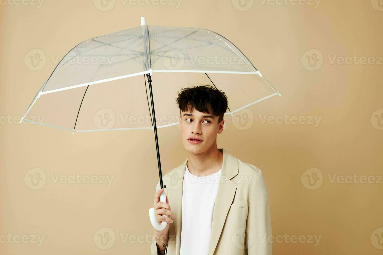 a man with an open umbrella in a jacket protection from the rain beige background photo