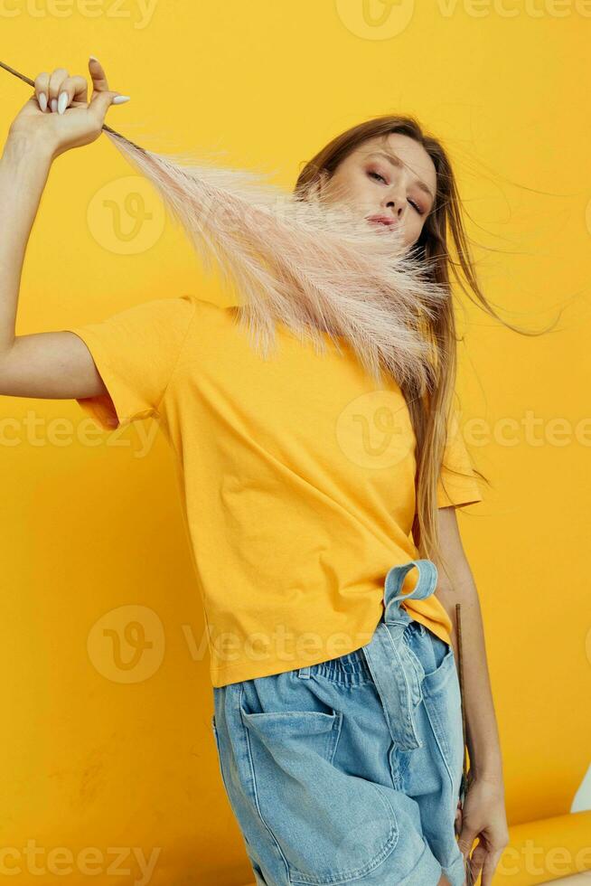 beautiful woman posing pink feathers in hands charm fashion yeah yellow background photo