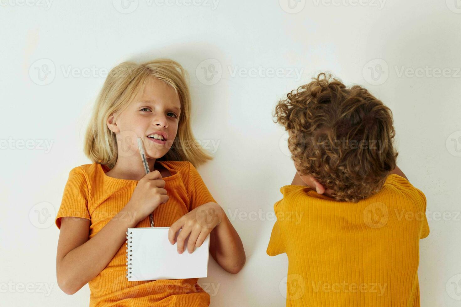Boy and girl on the floor with notepads and pencils isolated background unaltered photo