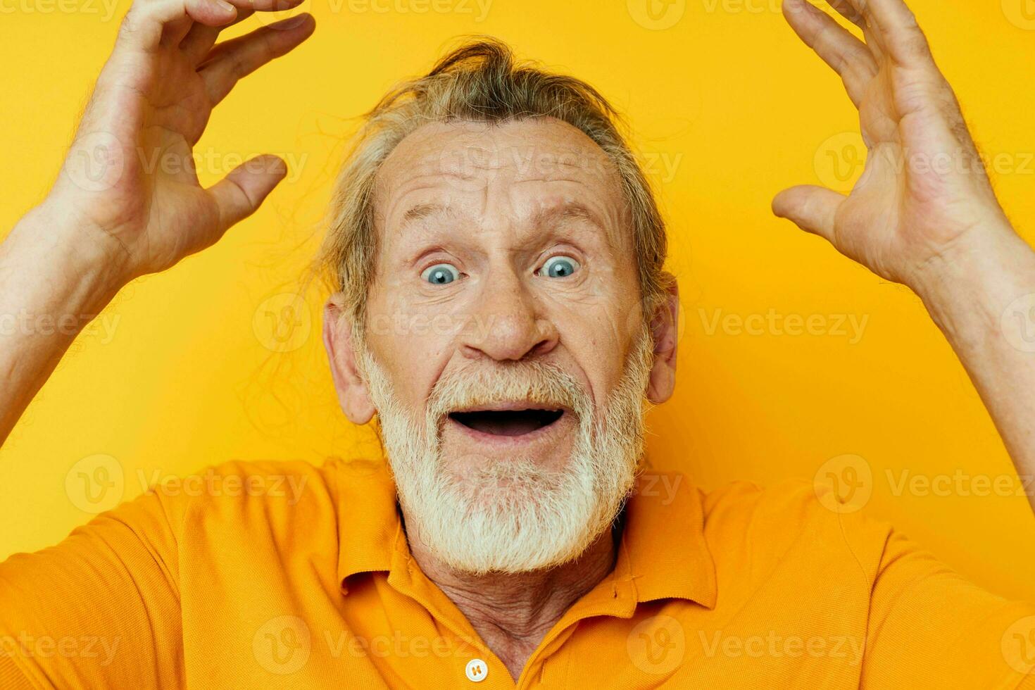 Senior grey-haired man with a gray beard emotion gestures hands yellow background photo