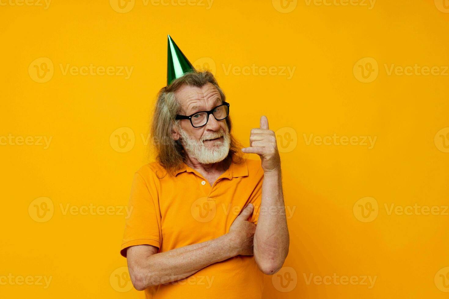 Senior grey-haired man wearing glasses green cap on his head holiday emotions yellow background photo