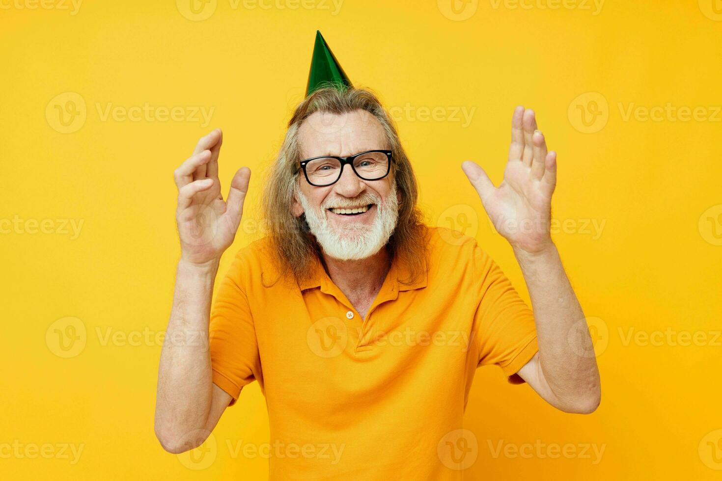 mayor canoso hombre vistiendo lentes verde gorra en su cabeza fiesta emociones amarillo antecedentes foto