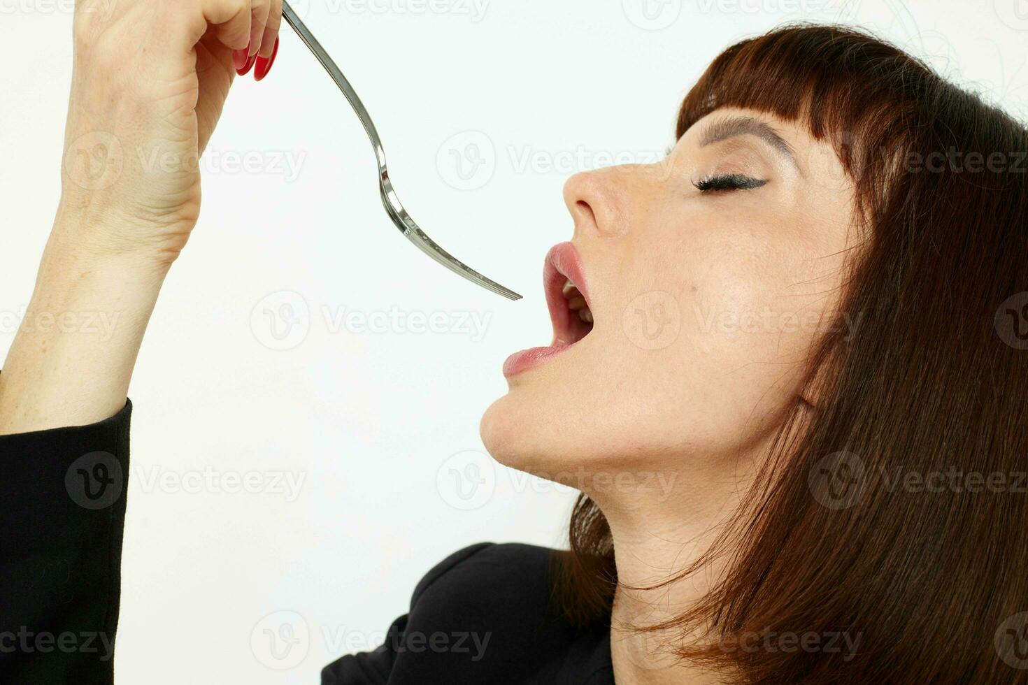 retrato de un mujer en un negro chaqueta un cuchillo y un tenedor cerca el cara estilo de vida inalterado foto