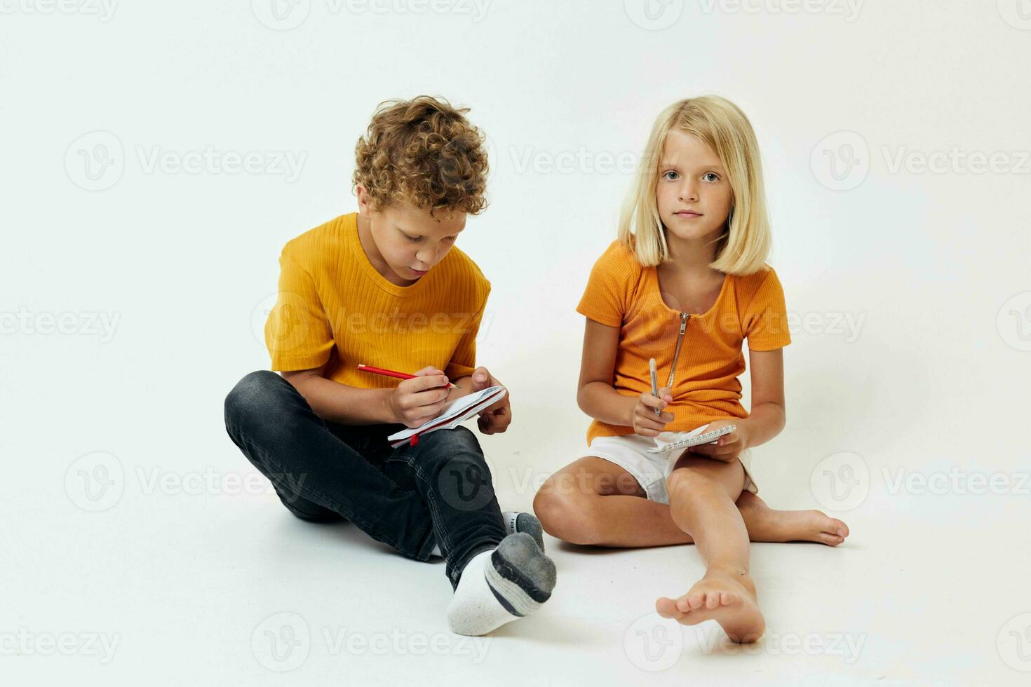 Boy and girl on the floor with notepads and pencils isolated background unaltered photo