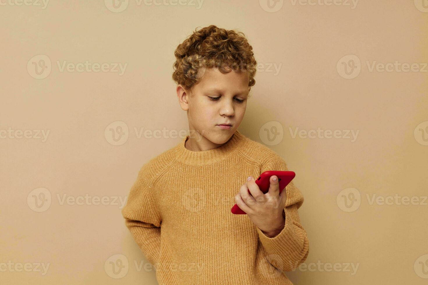 boy in a sweater with a phone in his hands technology beige background photo