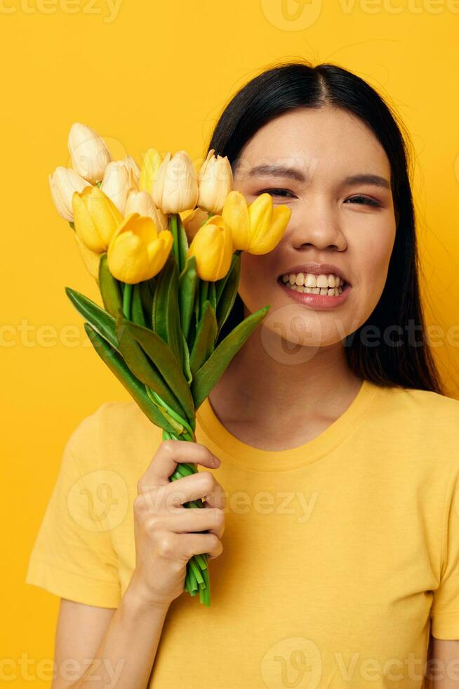 Portrait Asian beautiful young woman bouquet of flowers in hands spring fun posing yellow background unaltered photo