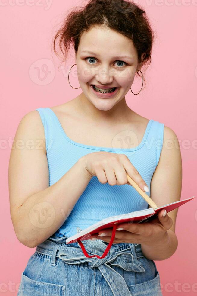teenager girl in a blue T-shirt with a red notepad and a pen of emotions isolated background unaltered photo