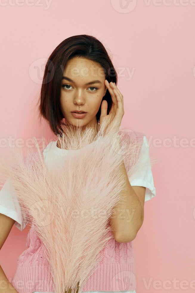 photo pretty girl in a pink vest with feathers in his hands isolated background