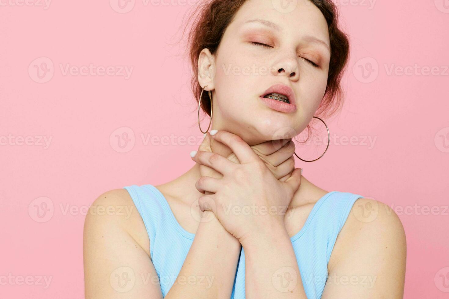 woman in blue t-shirt strangles herself emotions pink background photo