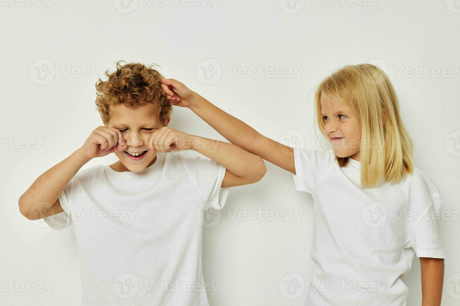 Little boy and girl in white T-shirts are standing next to isolated background photo