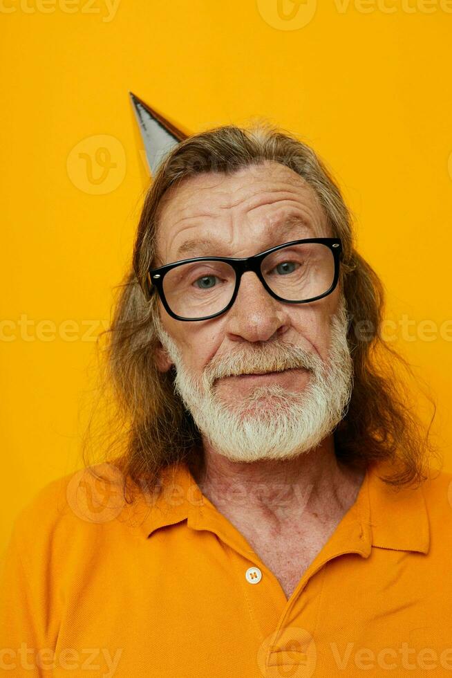 elderly bearded man wearing glasses with a cap on his head yellow background photo