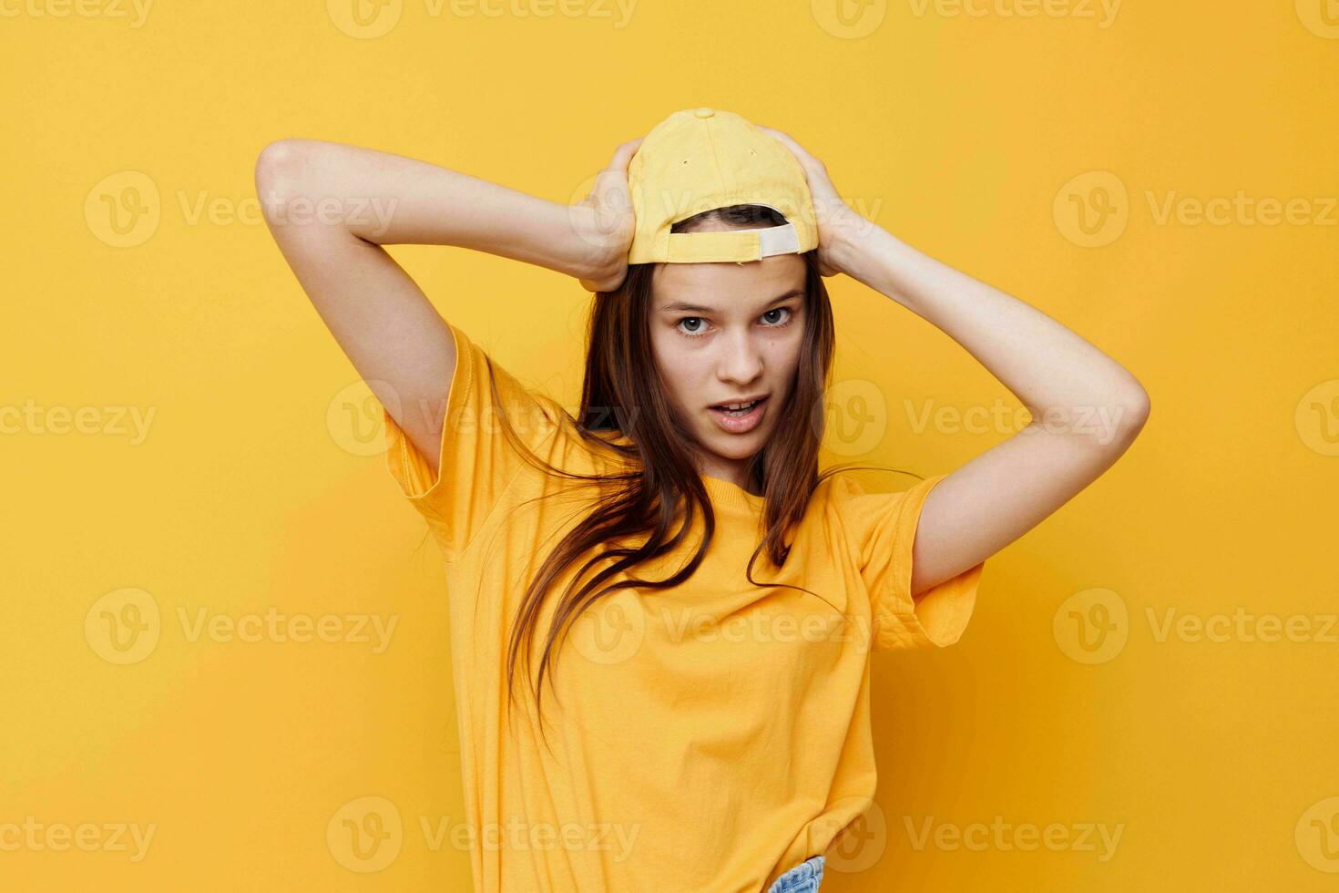 optimista joven mujer posando en un amarillo camiseta y gorra amarillo antecedentes foto