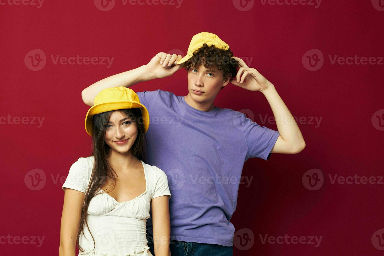 young man and girl in colorful t-shirts stylish clothes hats red background photo