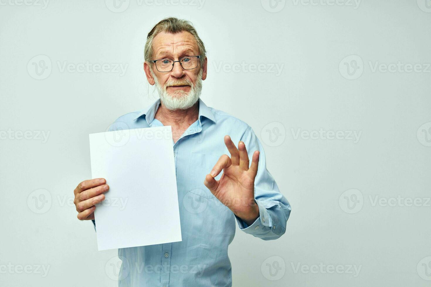 Senior grey-haired man holding a sheet of paper copy-space posing isolated background photo