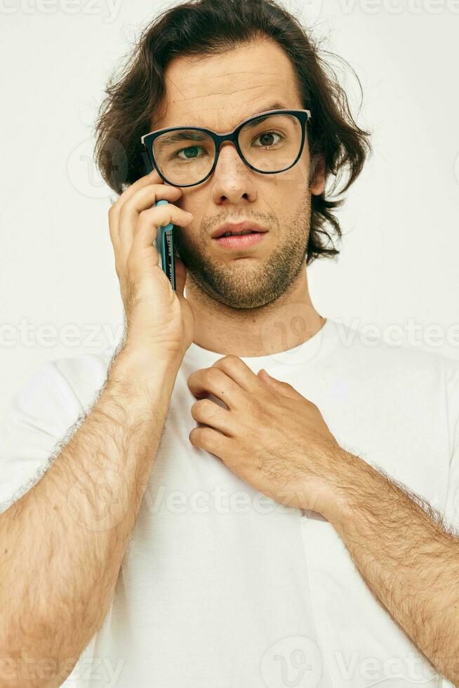 handsome man in a white T-shirt communication by phone light background photo
