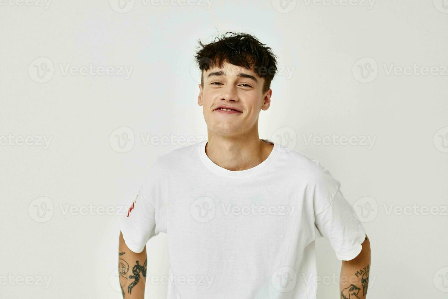 A young man tattoo on hands in white t-shirt light background unaltered photo